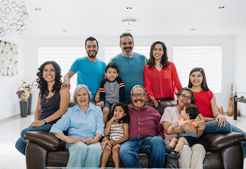 Senior Latino couple enjoying weekend with their grandchildren and family at home in summertime.