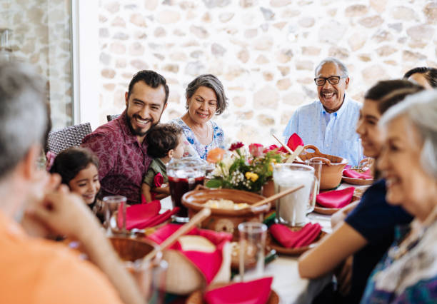 Multi generation Latin American family having family lunch together in summer Latino family enjoying weekend with their grandchildren and family at home in summertime. big family table stock pictures, royalty-free photos & images