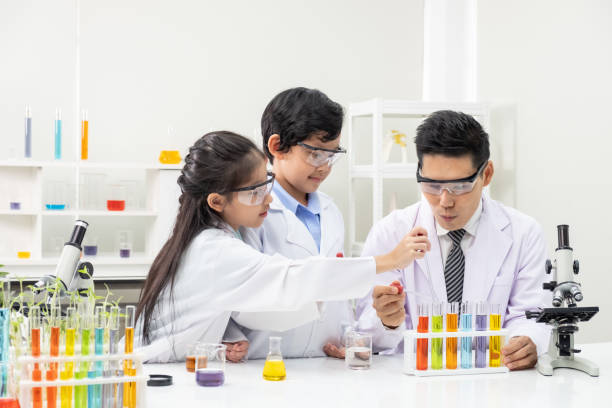 istock Young Asian boy and girl smile and having fun while learning science experiment in laboratory with teacher in classroom. Study with scientific equipment and tubes. Education concept. 1273425536