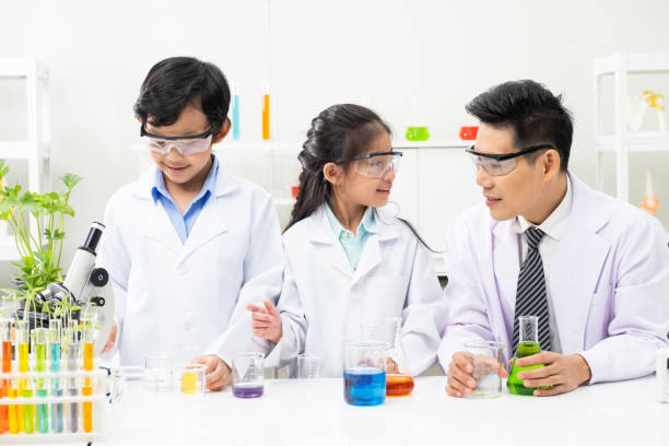 istock Young Asian boy and girl smile and having fun while learning science experiment in laboratory with teacher in classroom. Study with scientific equipment and tubes. Education concept. 1273425689