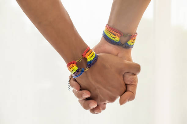 primo scatto della coppia asiatica maschile che si tiene per mano con braccialetti di sensibilizzazione arcobaleno gay pride. lgbt, amore omosessuale e relazioni omosessuali con lo spazio copia. - gay pride wristband rainbow lgbt foto e immagini stock