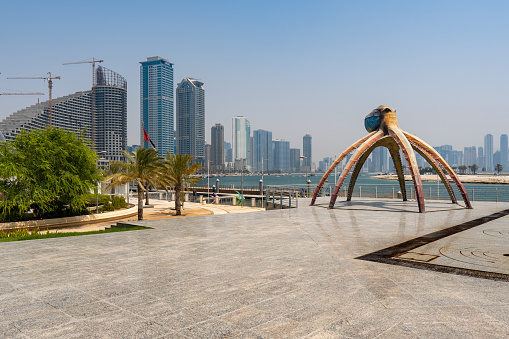 Sharjah Corniche or Promenade by the Sharjah Aquarium on a blue sky sunny day looking to the skyline near Dubai in the United Arab Emirates.