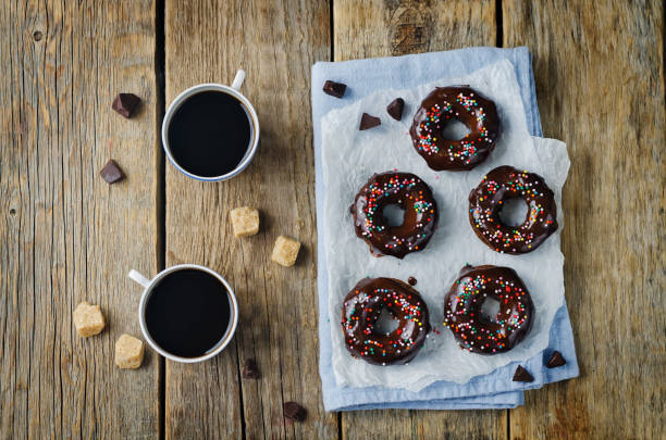 istock Baked chocolate doughnuts with chocolate glaze and multi color sprinkles 1273432400