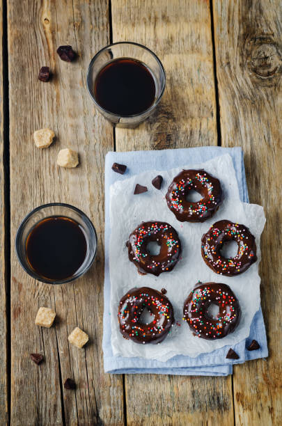 istock Baked chocolate doughnuts with chocolate glaze and multi color sprinkles 1273432421