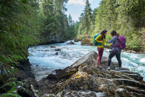 istock Sisters Checking Smart Watch for Navigation Trail App Along Riverbank 1273438905