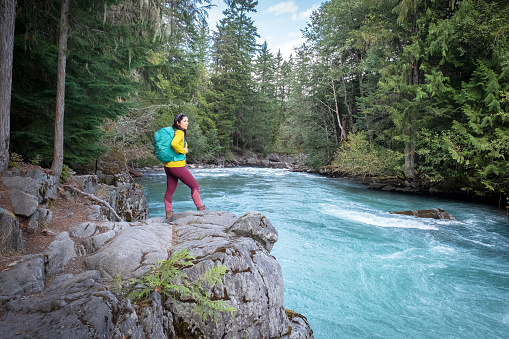 Eurasian woman enjoying the view of a turquoise, glacier fed river in Whistler, British Columbia, Canada.