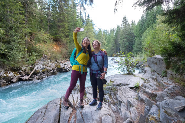 Hiking Sisters Taking Selfie on Rocky Ledge Near River