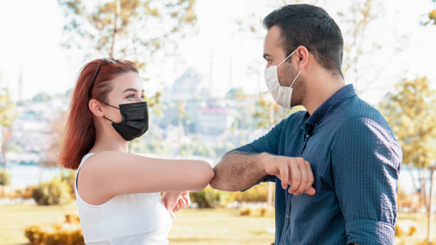istock Elbow bumping. A new way of greeting to avoid the spread of coronavirus (COVID-19). Two people (a man and a woman) bump elbows instead of hug or handshake 1273441849