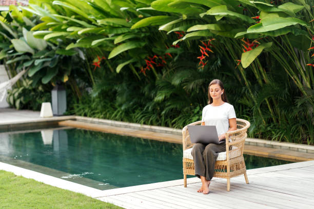 istock Young woman near swimming pool and working at latop computer 1273442897