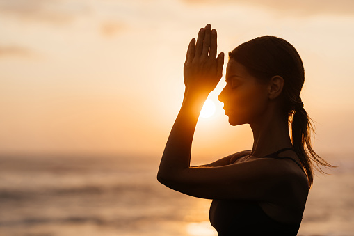 Yoga at sunset on the beach. woman performing asanas and enjoying life on the ocean. Bali Indonesia.