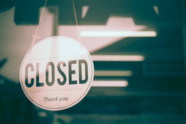Text on white signboard  "closed"u201d in front of the mirror"u2019s  shop. This shop was dark and closed because of the bankruptcy. stock photo