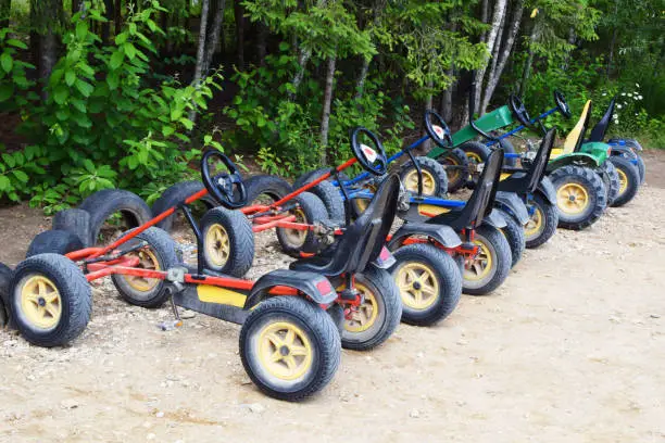 Many pedal kart for rent or sharing outdoors in city park, garden or forest. Healthy family outside sport recreation activities. Fun children cycle transport.