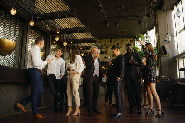 les gens d’affaires d’entreprise ayant du plaisir et de parler ensemble dans la fête d’entreprise dans le club pour célébrer l’événement spacial tel que l’aniversary d’entreprise - champagne flute champagne black wineglass photos et images de collection