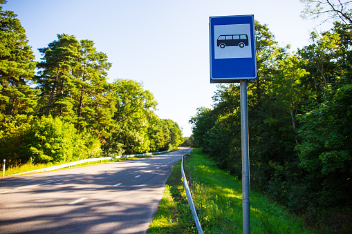 travel concept - bus stop with blue sign on forest road