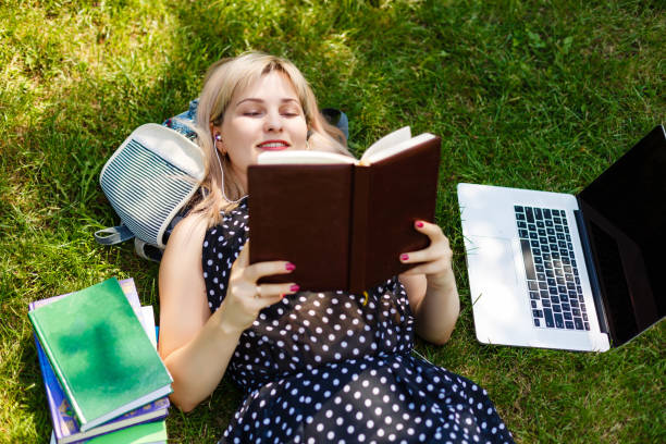 istock college student lying down on the grass working on laptop at campus 1273447787