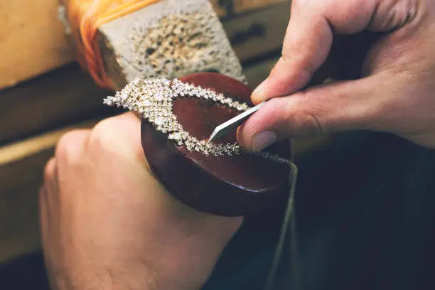 Photo of Jeweler making handmade jewelry on vintage bench. The art of jewelry. Jeweler making handmade necklace