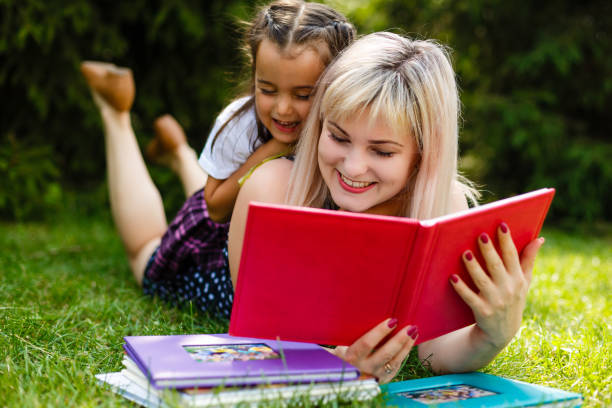 istock Mother and daughter reading a book at the park. 1273450096