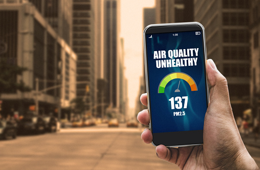 Air quality pollution app on smartphone in downtown city street indicating unhealthy air - climate change concept