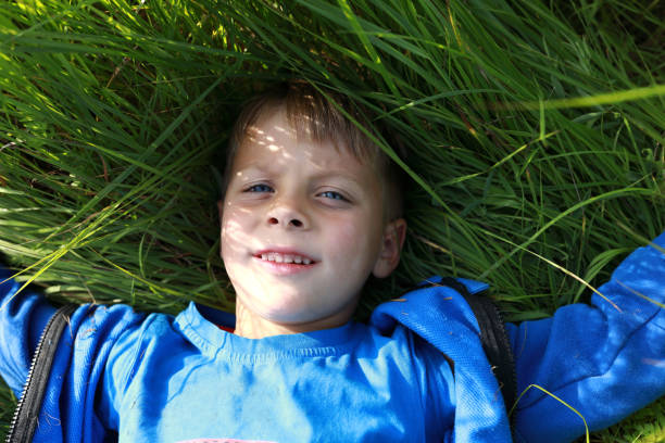 istock Boy lying on green grass of lawn 1273458570