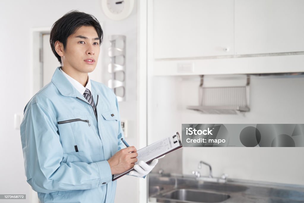 Japanese male worker checking the equipment in the room Coveralls Stock Photo
