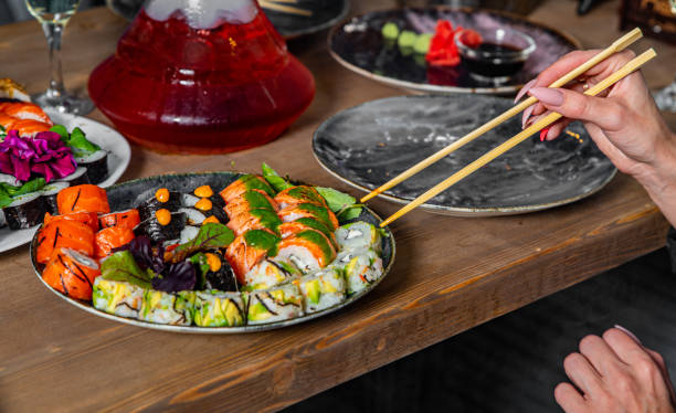 istock hand take sushi roll in plate on wooden table background 1273462159