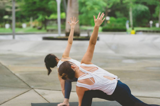 istock Two Young women practicing yoga in public park 1273463209