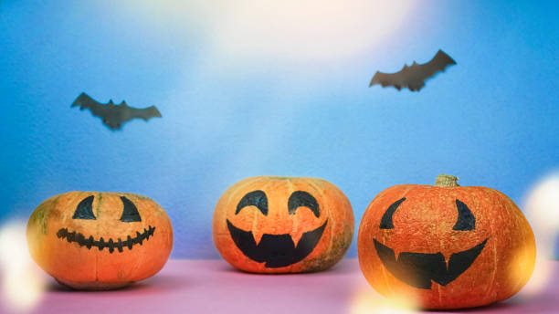 istock Blurred Halloween creative funny pumpkins with smile faces and paper bats 1273463367