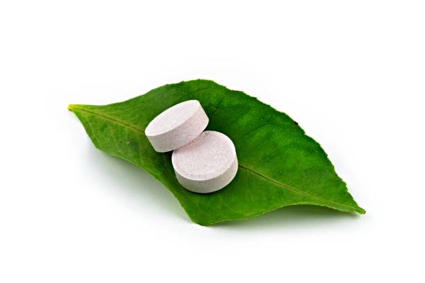 istock Green leaf and vitamin pills on white background. 1273465626