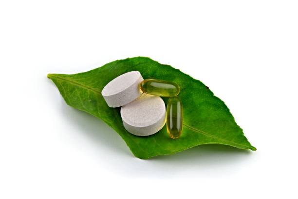 istock Green leaf, vitamin capsules and vitamin pills on white background. 1273465654