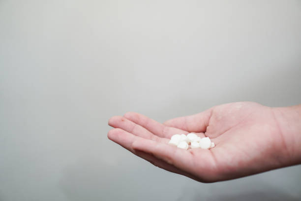 istock A woman's hand holding white pills on the white background. 1273465980