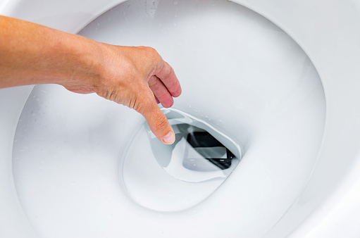 La mujer dejó caer su teléfono inteligente en el inodoro del baño. Teléfono en wc, concepto. photo