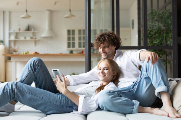 istock Couple in love relax on couch using digital tablet together at home. 1273470864