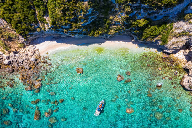 A small, secluded beach at Lixouri on the island of Kefalonia, Greece A small, secluded beach at Lixouri on the island of Kefalonia, Greece, with a fishing boat over crystal clear, turquoise sea lixouri stock pictures, royalty-free photos & images