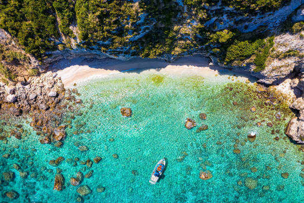 A small, secluded beach at Lixouri on the island of Kefalonia, Greece A small, secluded beach at Lixouri on the island of Kefalonia, Greece, with a fishing boat over crystal clear, turquoise sea kefalonia stock pictures, royalty-free photos & images