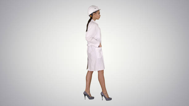 istock Woman in white robe putting hard hat on while walking on gradien 1273472732
