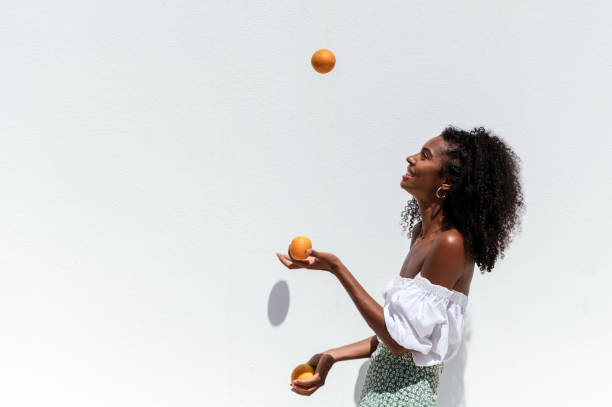 vrolijke zwarte vrouw met verse sinaasappelen - jongleren stockfoto's en -beelden