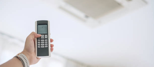 istock hand using remote controller for adjust Air conditioner inside the room of office or house 1273474019