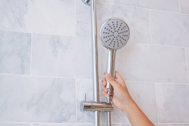 istock Hand holding shower head during taking shower with marble wall background in modern bathroom 1273474304