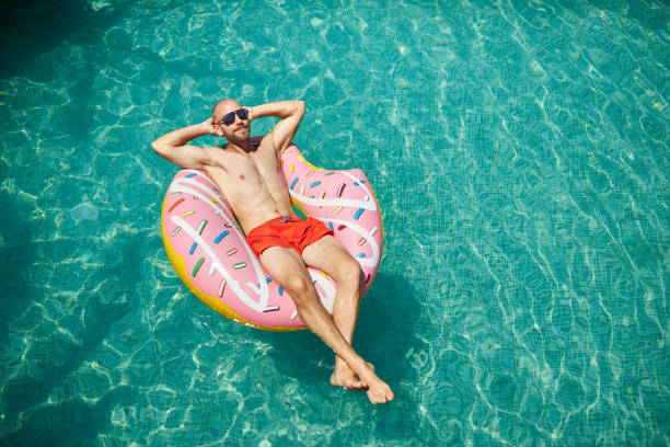 istock A trained middle-aged man is lying on an inflatable donut with red swimming trunks and sunglasses in the pool, enjoying his vacation. 1273477877