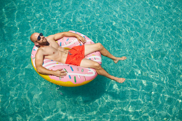 istock A trained middle-aged man is lying on an inflatable donut with red swimming trunks and sunglasses in the pool, enjoying his vacation. 1273477908