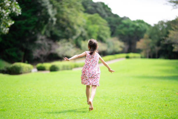 girl playing barefoot on the lawn - child rear view running nature imagens e fotografias de stock