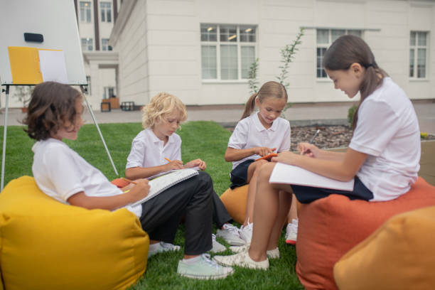 istock Children sitting together on bag chairs and doing homework 1273478965