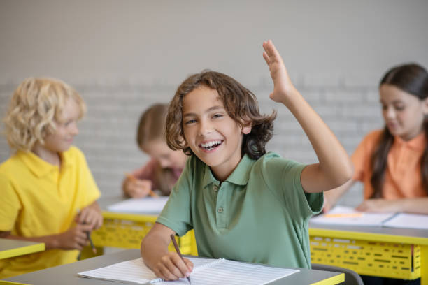 istock Dark-haired boy raising his hand ready to answer 1273479027