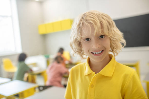 istock Cute schoolboy in yellow tshirt smiling nicely 1273479046