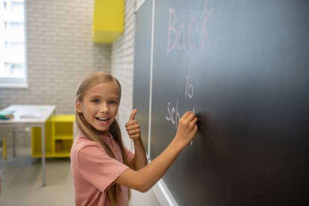 istock A girl in pink tshirt writing on the blackboard 1273479049
