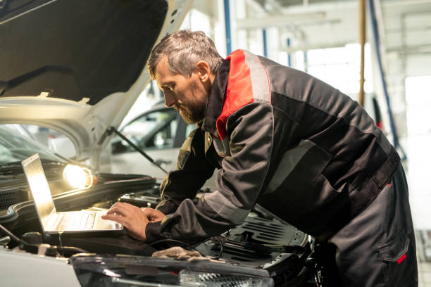 istock Middle aged male worker of car maintenance service bending over engine 1273479120