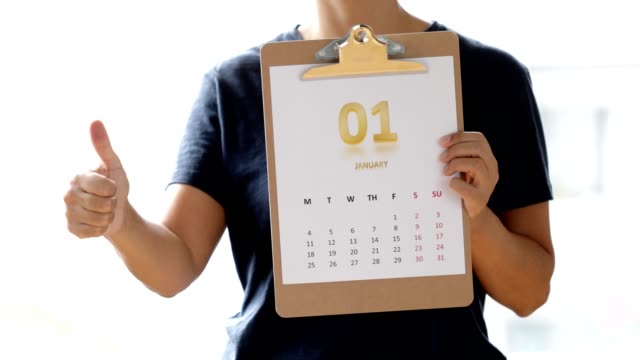 Woman showing thumbs next to monthly calendar of January