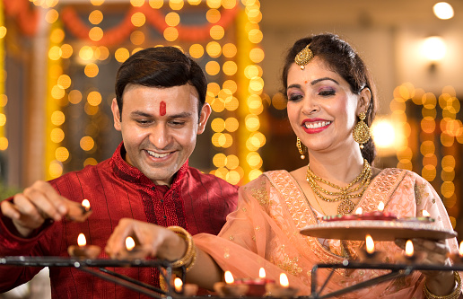 Happy Indian couple decorating with Diya oil lamps on the occasion of Diwali festival celebration