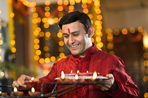 Happy Indian man decorating with diya oil lamps on the occasion of Diwali festival celebration