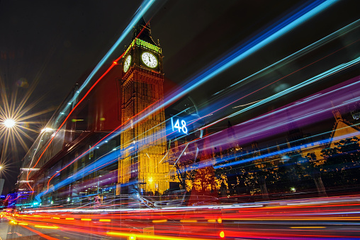 A nighttime long exposure of Big Ben, with light trails and the faint image of a bus